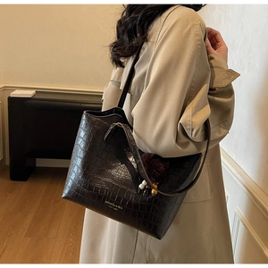 Detail of vintage brown crocodile embossed leather bucket bag with plush charm and gold logo