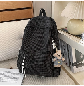 Close-up of black and white checkered canvas backpack with a cute brown plush bear charm