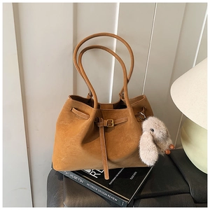 Close-up of brown suede tote bag with drawstring detail and a cute plush rabbit charm