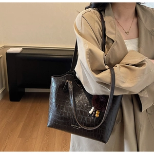 Detail of dark coffee crocodile texture bucket bag with fuzzy ball charm and wooden beads