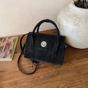 Detail view of black vintage crossbody bag with silver twist lock on wooden surface