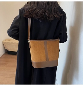 Detailed view of brown faux suede bucket bag shown on shoulder for size and styling