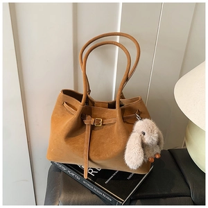 Detail of vintage brown suede tote bag featuring slim handles and plush bunny charm