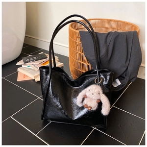 Close-up of large black leather tote bag with glossy finish and cute bunny pendant