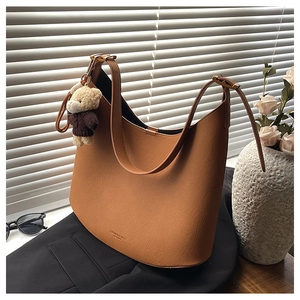 Détail du sac hobo marron caramel avec texture litchi et un joli pendentif ours en peluche