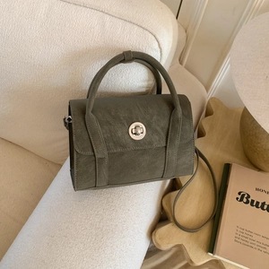 Close-up of olive green crossbody bag with silver twist lock on textured sofa