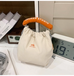 Detail of canvas tote bag featuring orange plush handle with SHILAIEN STUDIO logo