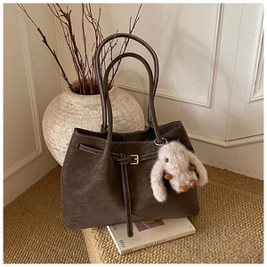 Detail of dark brown suede tote bag with slim straps and cute plush rabbit charm