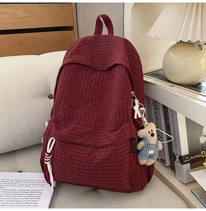 Detail of red checkered backpack with front zipper pocket and cute plush bear accessory