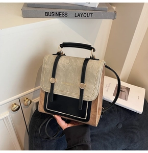 Close-up of retro color-block handbag with gold buckle and logo on a stylish table