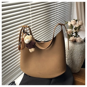 Sac hobo en cuir marron avec pendentif ours présenté dans un décor chaleureux