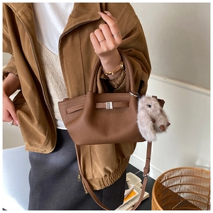 Detail of dark brown leather bucket bag with silver buckle and plush rabbit charm