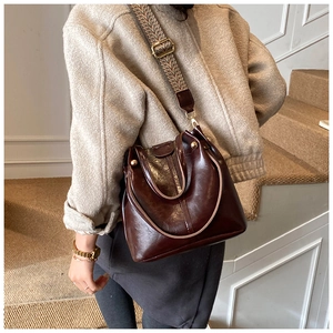 Detail of vintage bucket bag featuring a patterned wide shoulder strap and gold hardware
