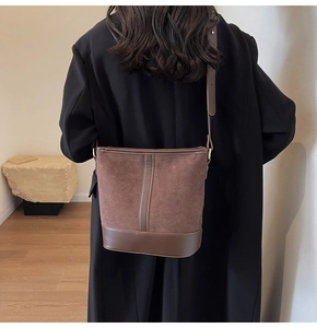 Detail of vintage bucket bag featuring suede texture and smooth leather strap on a model