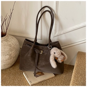 Detail of dark brown tote bag with contrast stitching and gray rabbit plush charm