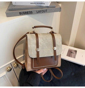 Detail of retro mini backpack showing brown leather straps and beige canvas texture
