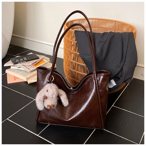 Detail of dark brown oil wax leather tote bag with a soft bunny plush charm