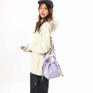 Detail of purple nylon drawstring crossbody bag with green lettering and logo handle