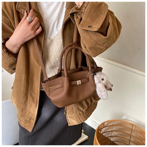Brown leather bucket bag with decorative strap and a cute plush puppy pendant