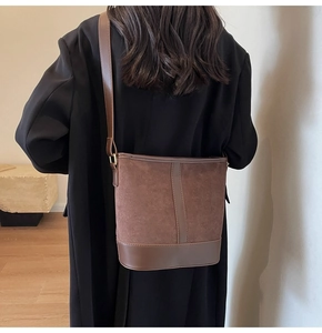 Detail of vintage brown suede bucket bag texture and leather trim on model