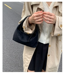 Detail of minimalist black suede hobo bag carried by model in a street style setting