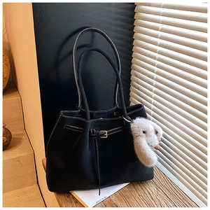 Detail of black suede tote bag featuring white contrast stitching and a plush rabbit charm
