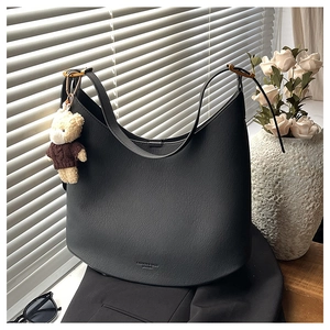Détail du sac hobo en cuir grainé noir avec un charm ours en peluche et boucle dorée