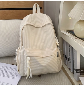 Detail of minimalist beige plaid backpack with drawstrings in a cozy room setting