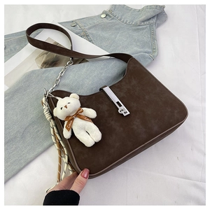 Detail view of brown faux suede shoulder bag with metal buckle and plush bear charm