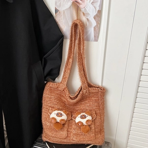 Detail of a brown knit tote bag featuring cute cat plush dolls on dual front pockets