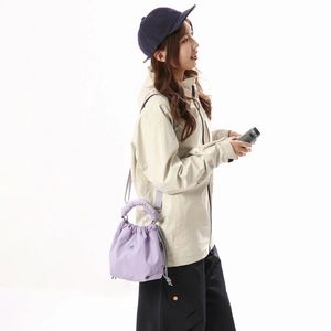 Detail view of purple nylon drawstring bucket bag with top handle and logo print