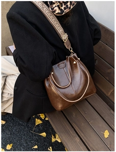 Detail einer braunen Retro-Beuteltasche mit gemustertem Gurt und Goldbeschlägen
