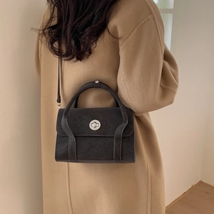 Detail of vintage grey leather satchel featuring a silver twist lock on wool coat