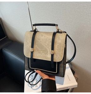 Detail of two-tone contrast bag with gold rivets and elegant brand lettering on the front