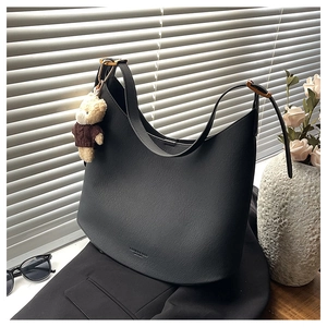 Détail du sac hobo en cuir grainé noir avec charme d'ours en peluche et bandoulière