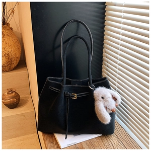 Detail of black tote bag with white contrast stitching and a plush rabbit charm