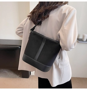 Rear view of model wearing a black matte suede bucket bag with leather accents