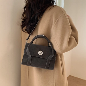Chic black retro shoulder bag styled with a classic camel coat for a modern commute look