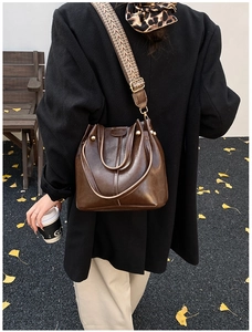 Close-up of retro dark brown bucket bag with patterned wide strap in autumn setting