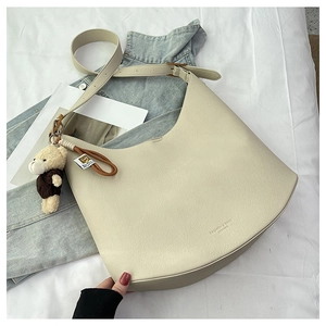 Détail du sac hobo en cuir blanc cassé avec pendentif ours sur fond en jean bleu