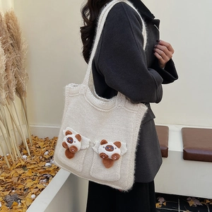 Detail of off-white knitted tote bag with plush cartoon charms and thick woven straps