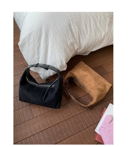 Détail des sacs hobo en daim noir et marron posés sur un parquet en bois chic