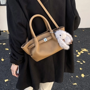 Detail of tan pebble leather bucket bag with silver lock and plush bunny charm
