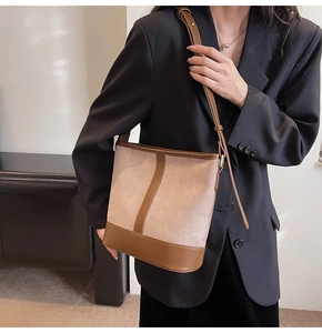 Detail view of the retro patchwork bucket bag worn over the shoulder on a black blazer