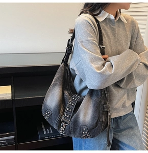 Close-up of washed denim tote bag featuring vintage silver studs and rivets on the shoulder strap