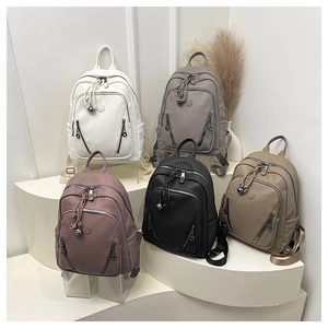 Five small faux leather backpacks in various colors displayed on white minimalist steps