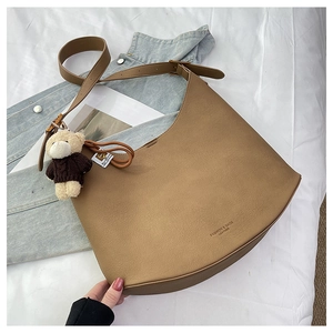 Détail du sac hobo kaki avec texture litchi, texte mode et un joli porte-clés ours