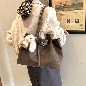 Detail view of dark brown faux suede tote bag with white stitching and rabbit charm