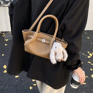 Detail of a brown leather bucket bag with silver buckle and rabbit plush pendant