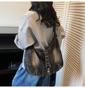 Detail of oversized washed denim hobo bag with silver rivets shown on a model